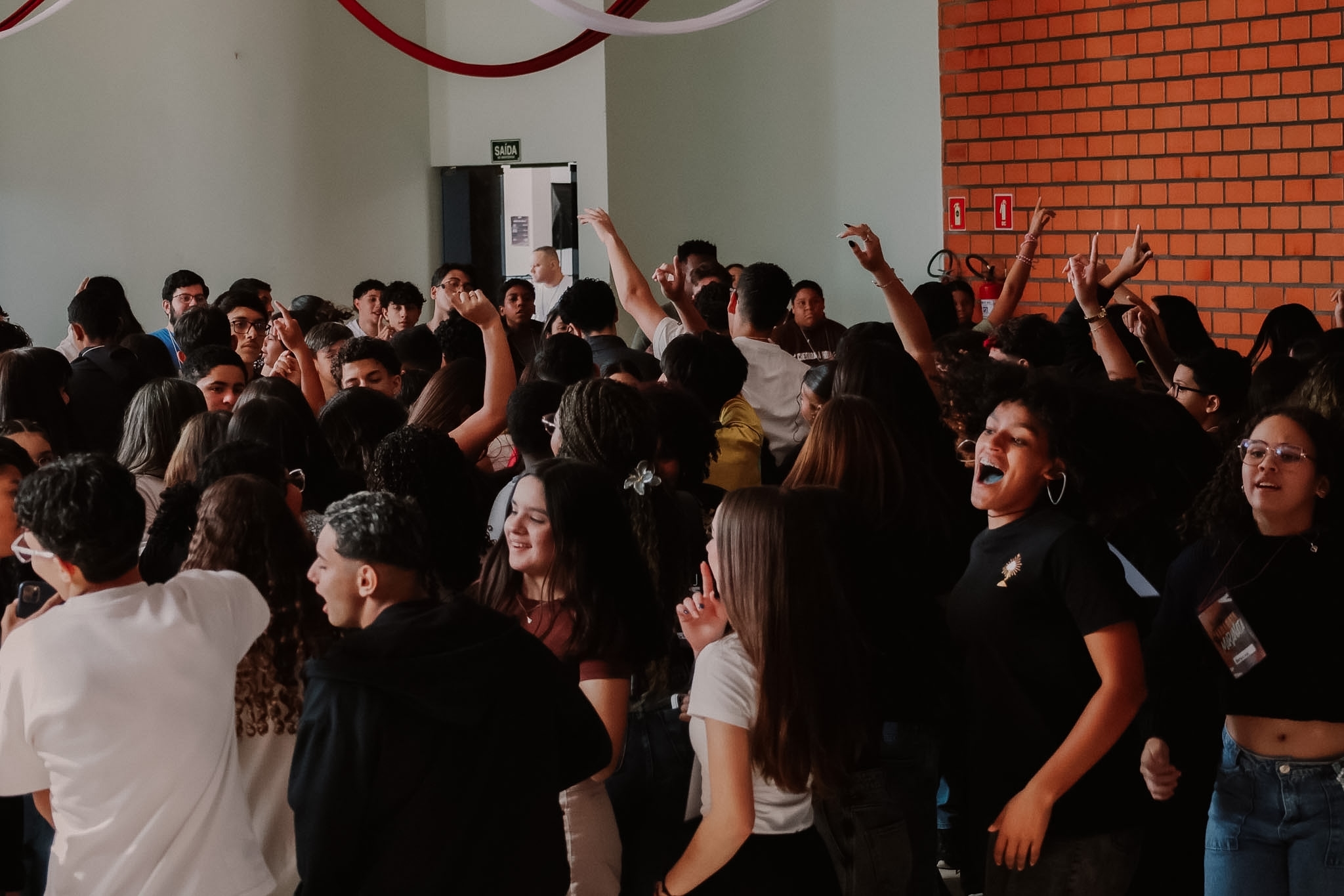 Grupo de jovens reunidos em oração, com os braços erguidos, no Retiro Maranata